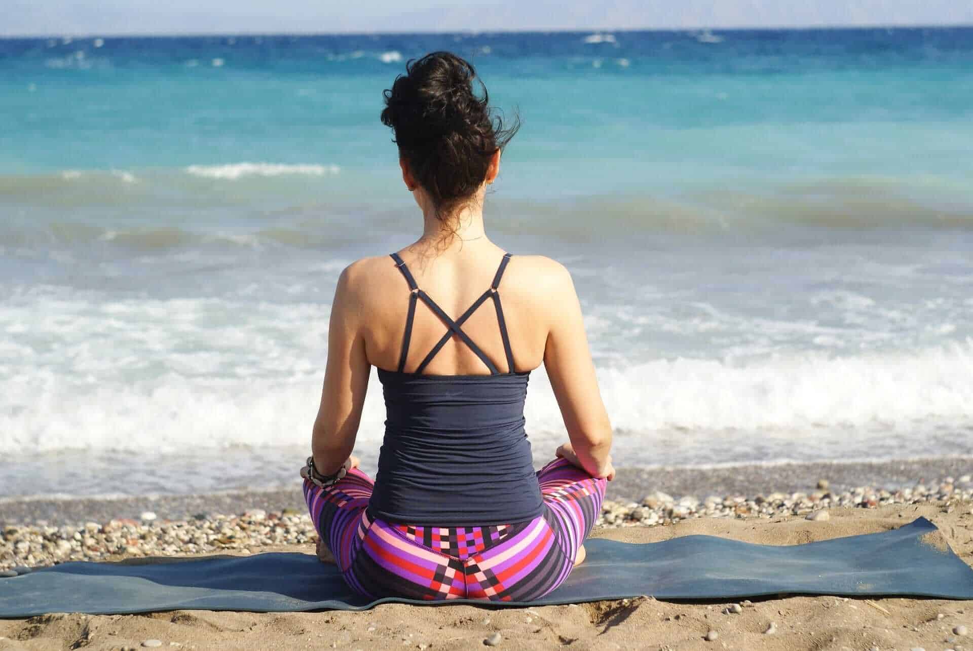 woman meditating near beach